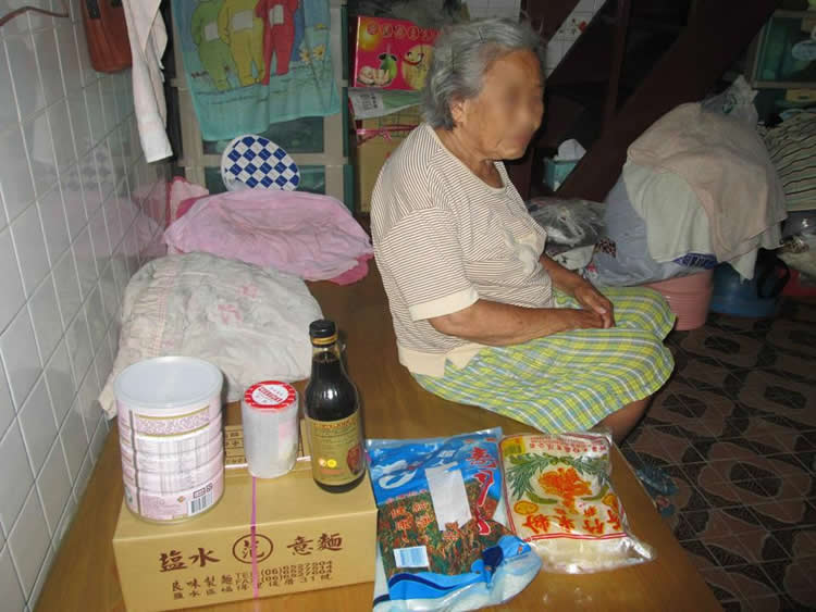 小小的斗室哩，擺著一張木板床，一旁是簡陋的廚房，飯桌上有些未吃完的麵條跟空罐頭。